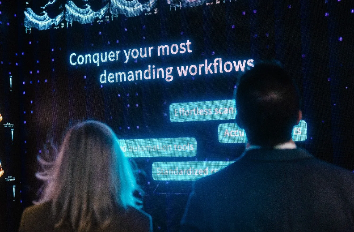 Conference attendees viewing a large branded presentation screen at a Nashville exhibit hall