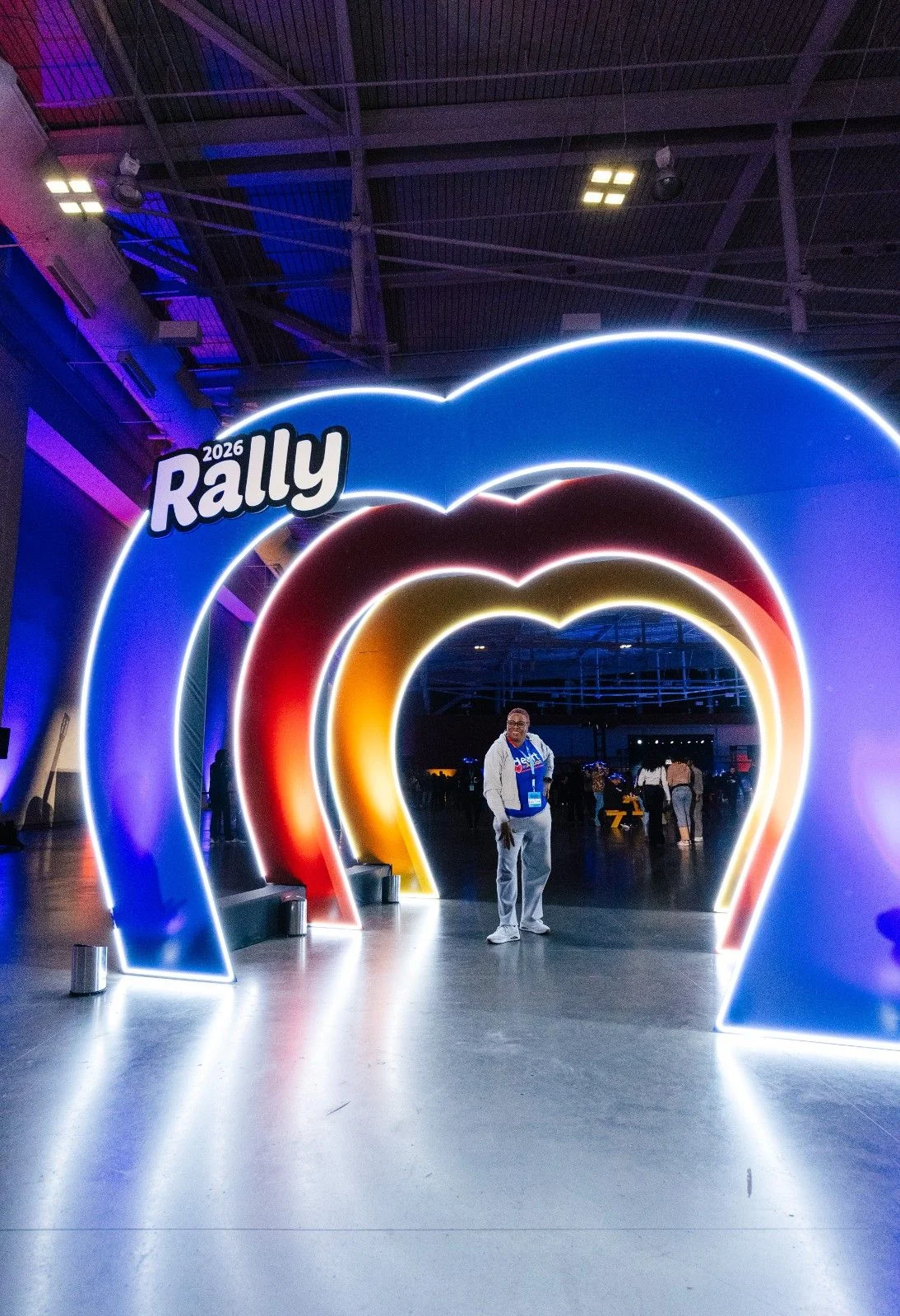 Attendee walking through a colorful illuminated arch installation at a Nashville conference