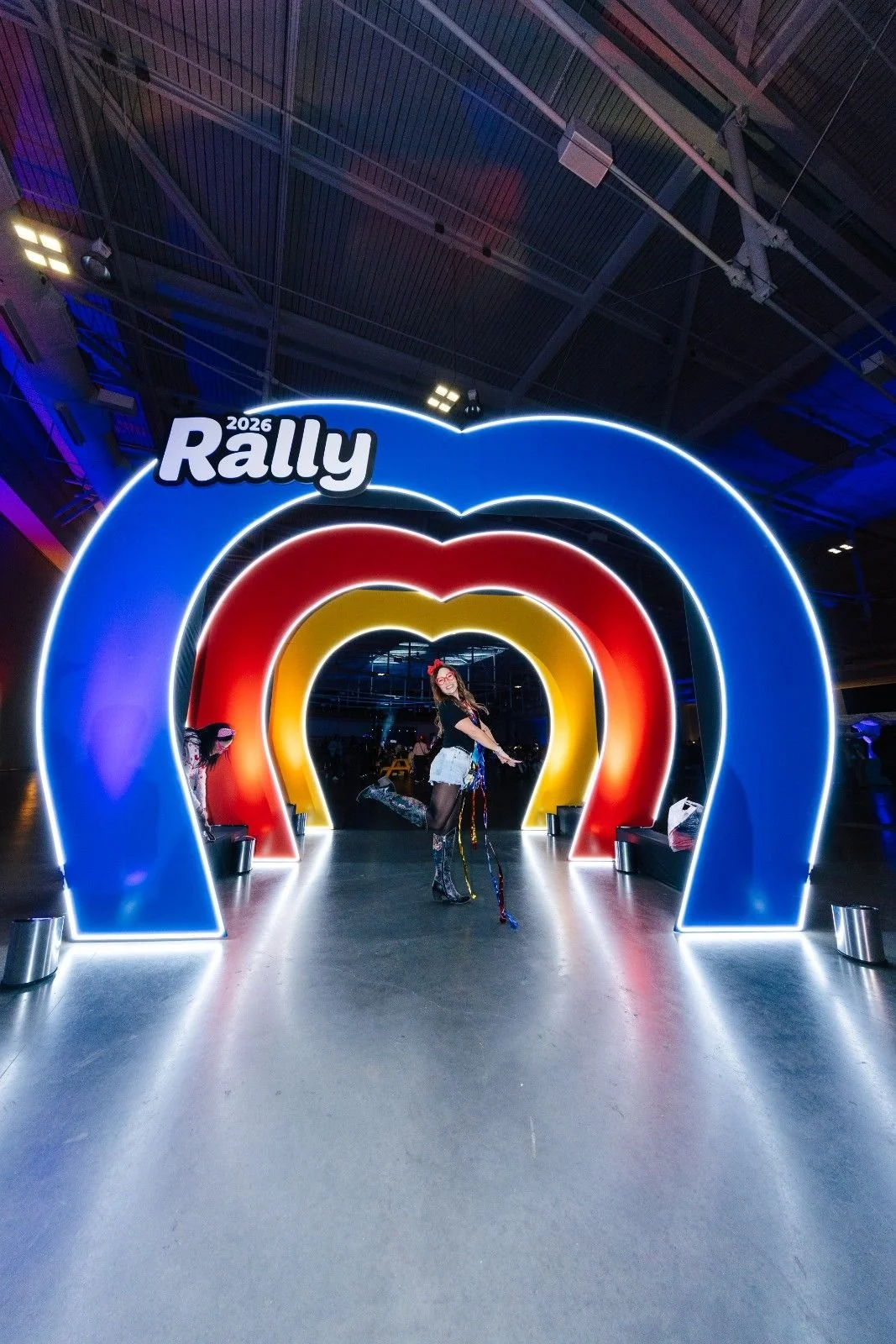 Attendee posing inside a colorful illuminated rainbow arch photo activation at a Nashville conference