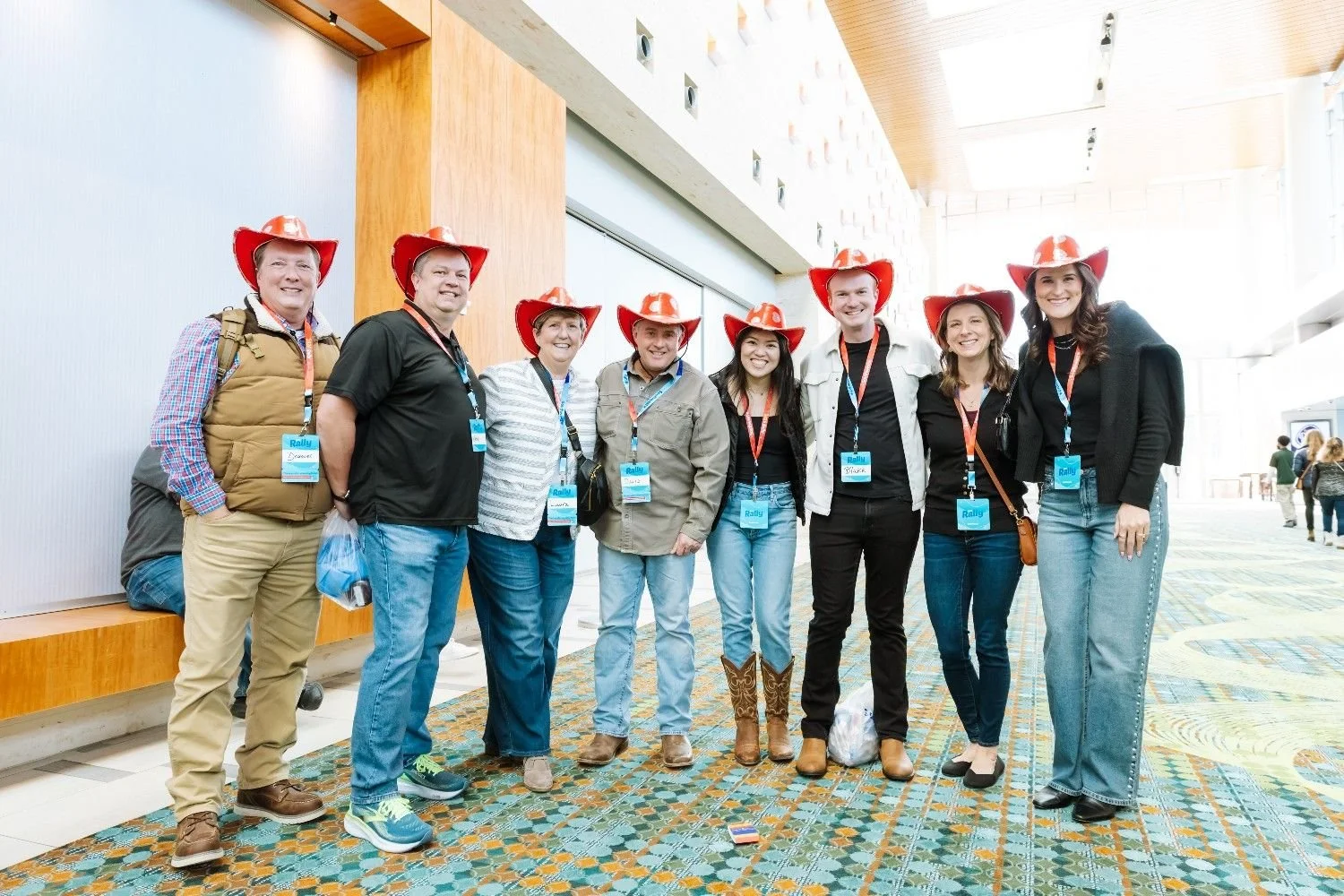 Group of conference attendees wearing red cowboy hats posing together in a Nashville convention center hallway