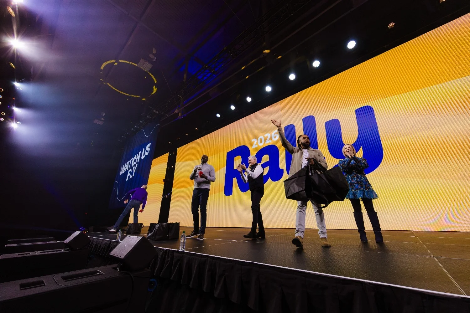 Performers celebrating on a brightly lit stage in front of a large crowd at a Nashville conference event