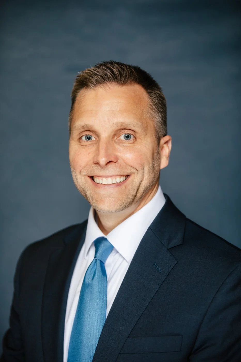 Confident businessman in a navy suit and blue tie during a corporate headshot session