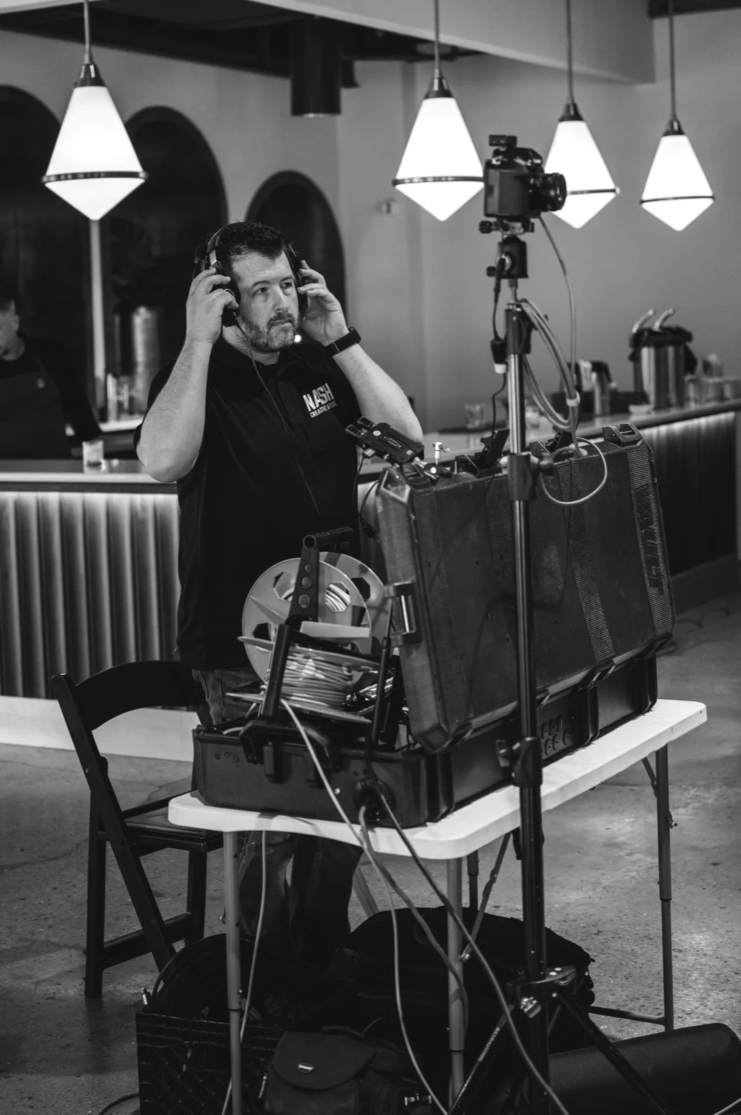 Audio technician adjusting headphones next to production gear at an event venue